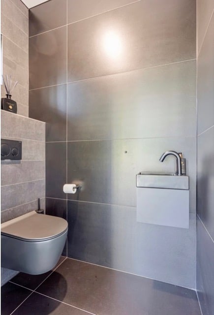 Moderne toiletruimte met grote grijze tegels